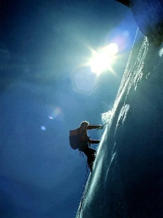 青い空と輝く太陽の下、氷壁を登る登山家