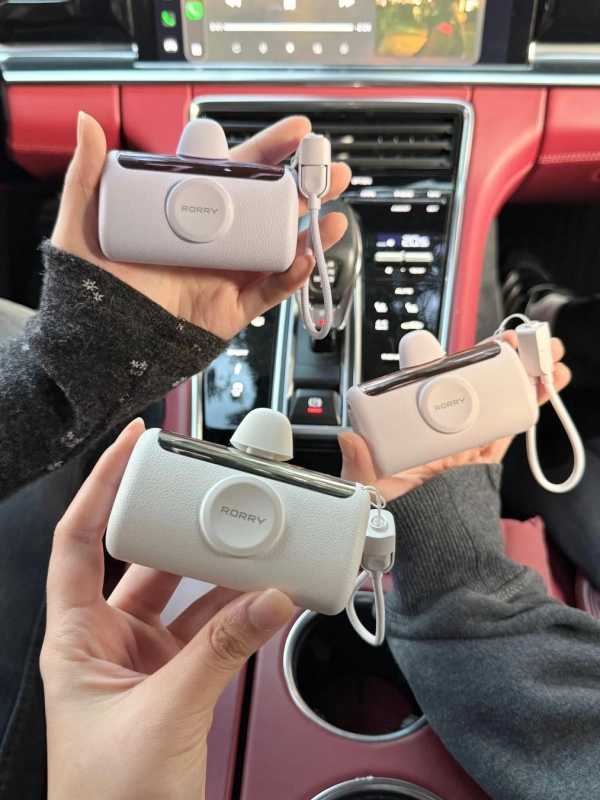 車内で複数の手が「RORRY」と書かれたデザイン性の高いポータブル充電器を持っている様子