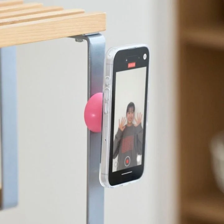 棚にスマホが固定され、画面には笑顔の女性が映る