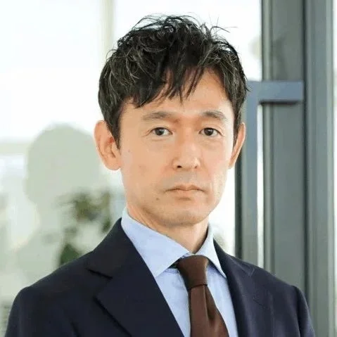 スーツを着用したアジア系の男性がカメラをまっすぐ見つめているポートレート写真