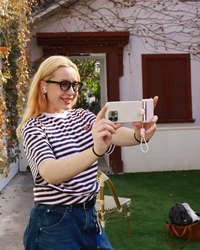 女性が屋外でスマートフォンを使って自撮りをしている様子