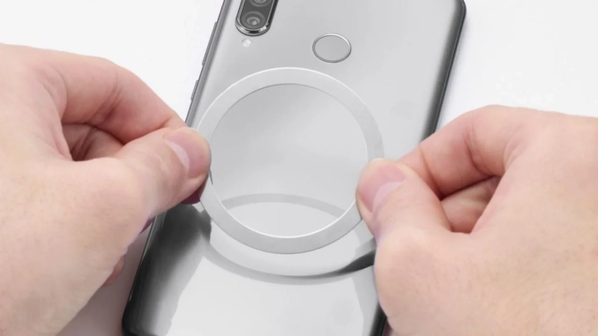スマートフォンの背面にリング状のアクセサリーを貼り付けようとしている様子