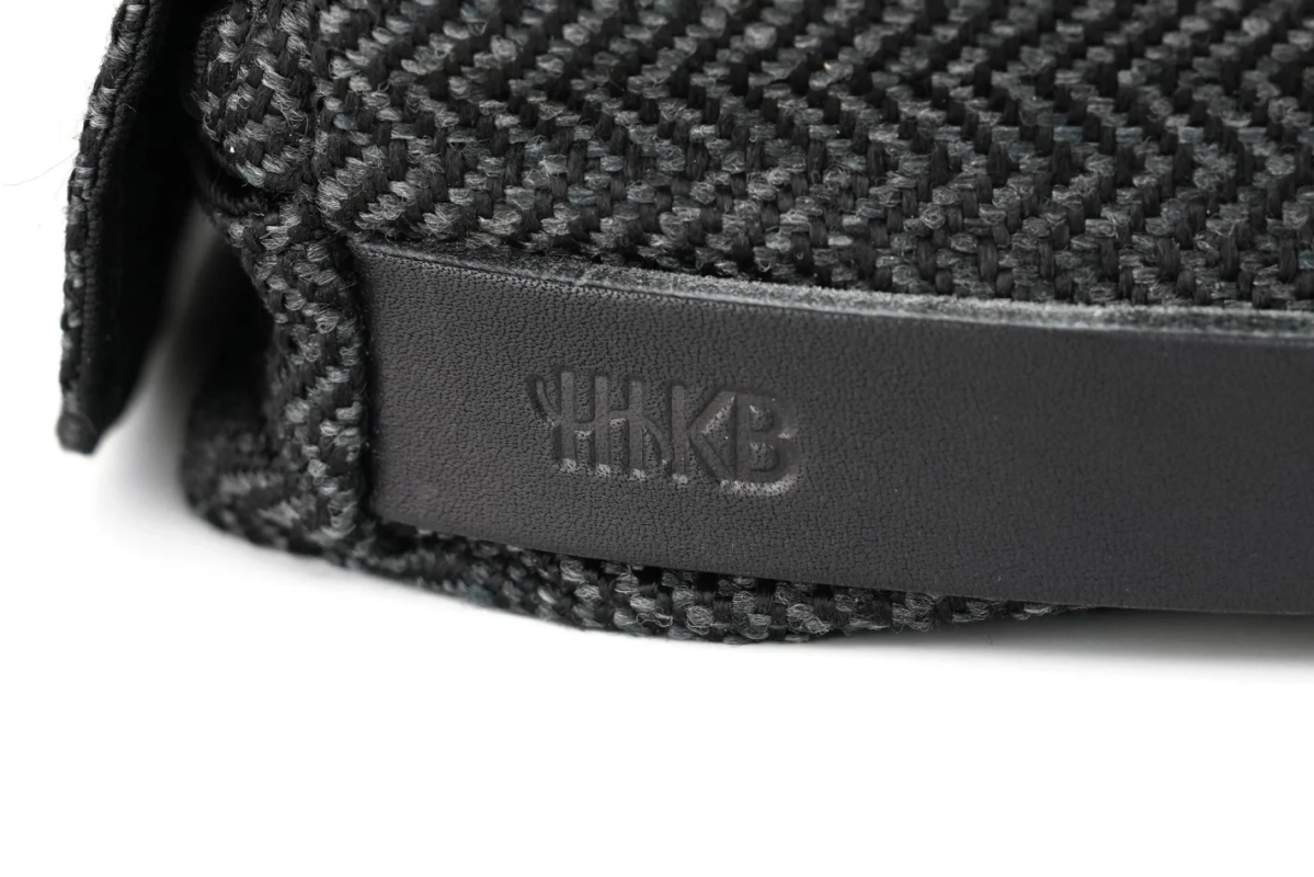 HHKBロゴがエンボス加工された黒い革のストラップとヘリンボーン柄の生地
