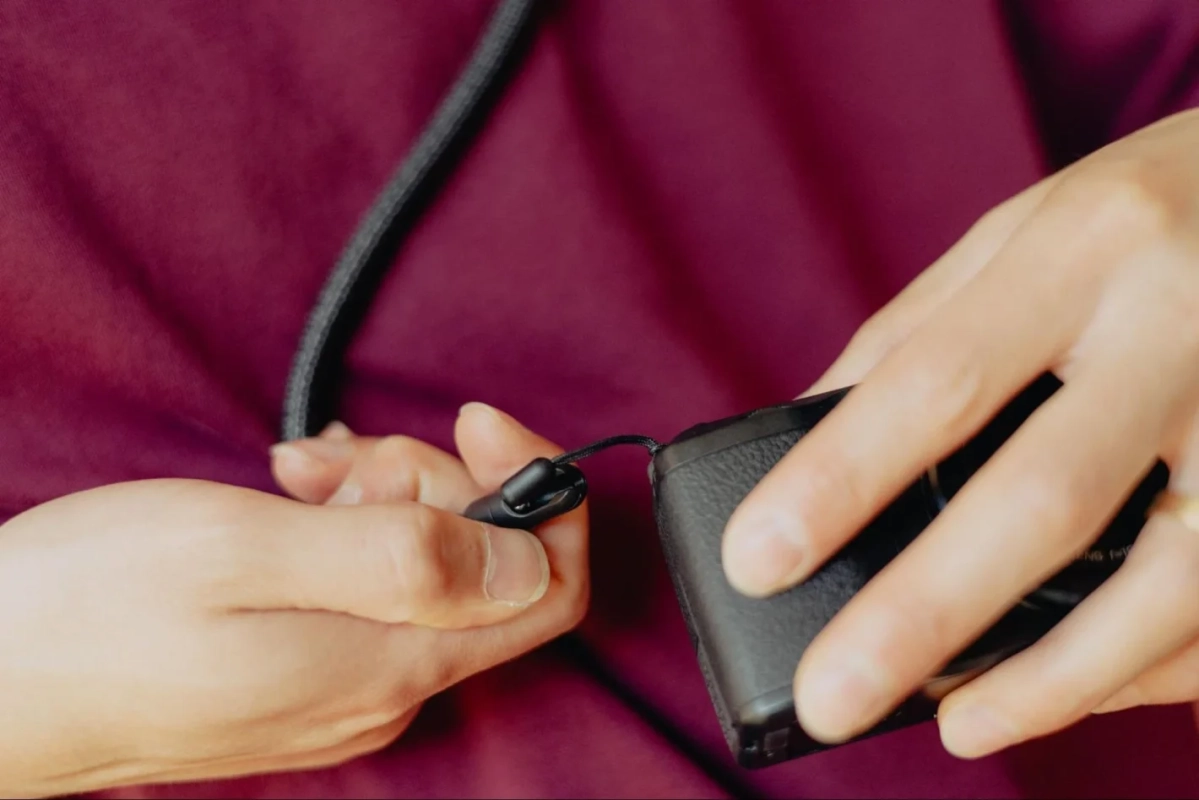 カメラにネックストラップを取り付けている手元