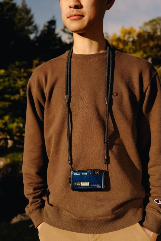 男性がNikon COOLPIXを首から下げている