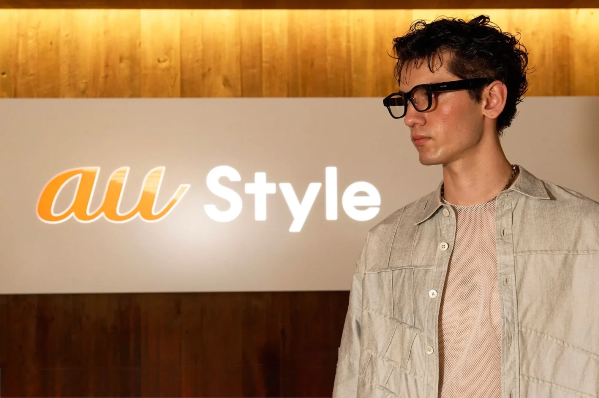 au Styleのロゴを背景にメガネをかけた男性