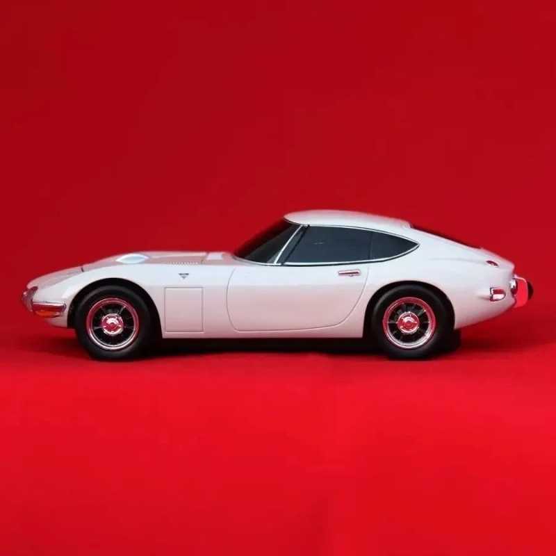 白いクラシックカー（トヨタ2000GT）が赤色の背景に横向きに写っている