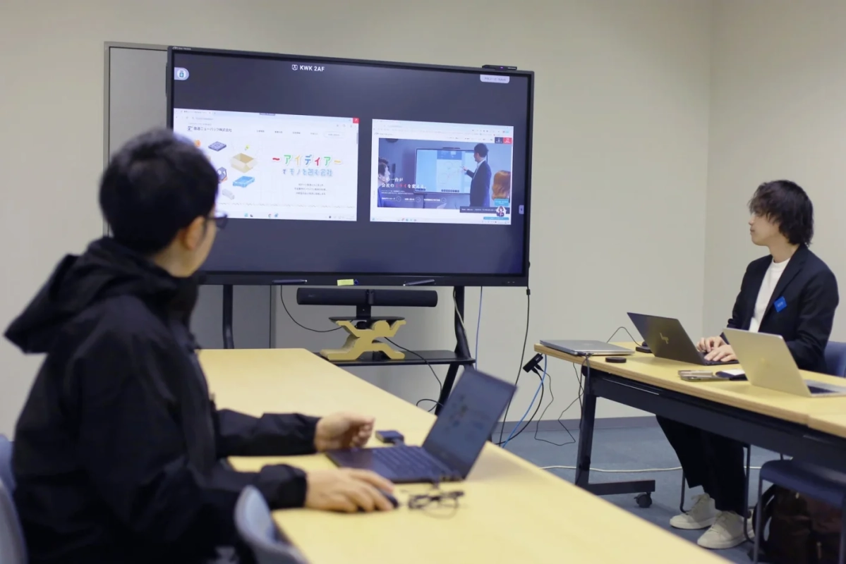 会議室で大型ディスプレイを見ながら作業する男性たち