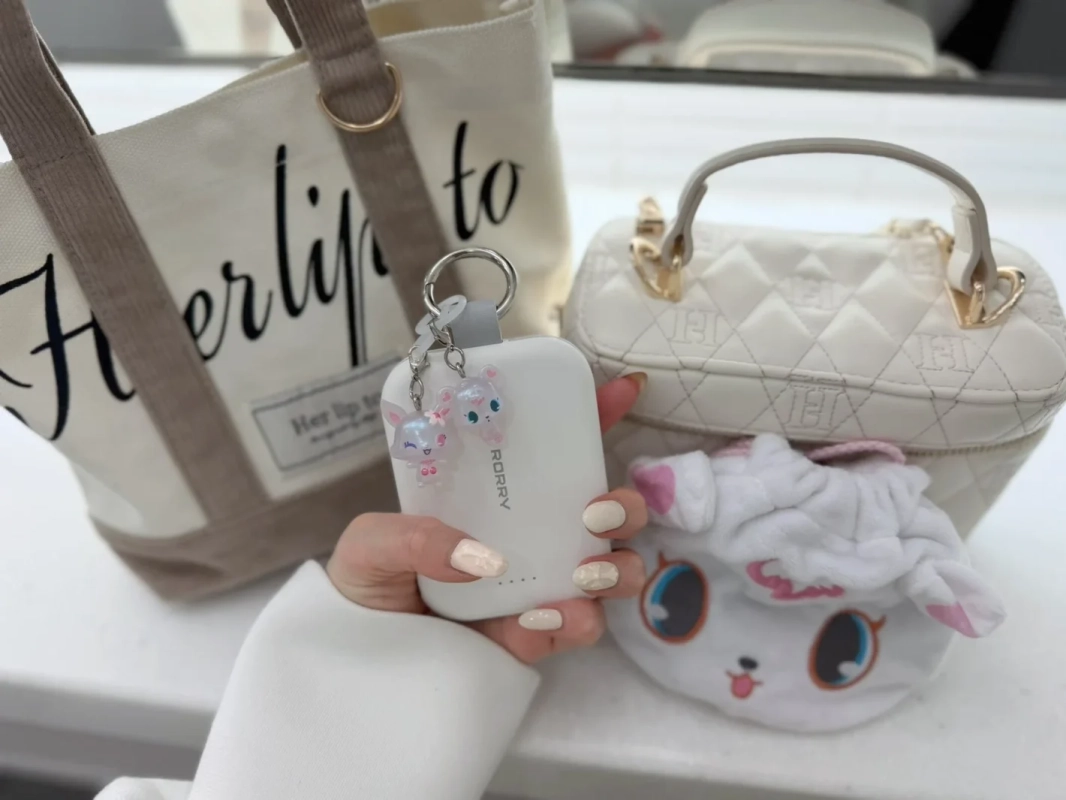 白いモバイルバッテリーを持つ女性の手