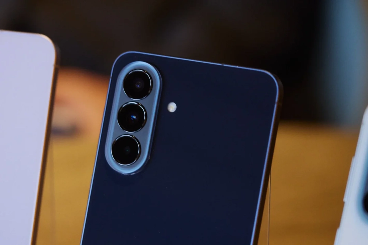 暗い青色のスマートフォンの背面をクローズアップで捉えた画像です。縦に並んだトリプルカメラとフラッシュが特徴的で、最新モデルのデザインを示唆しています。