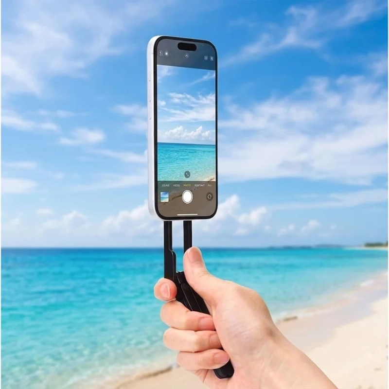 晴れた青空とエメラルドグリーンの海が広がるビーチで、スマートフォンを使い風景を撮影している様子です。