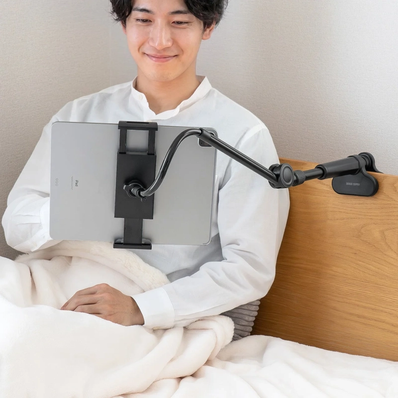 ベッドでタブレットを操作する男性