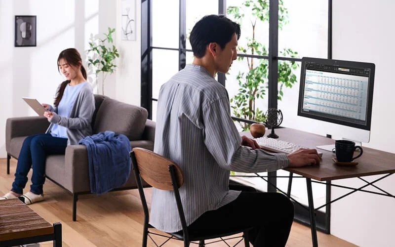 リビングでPCとタブレットを使用する夫婦