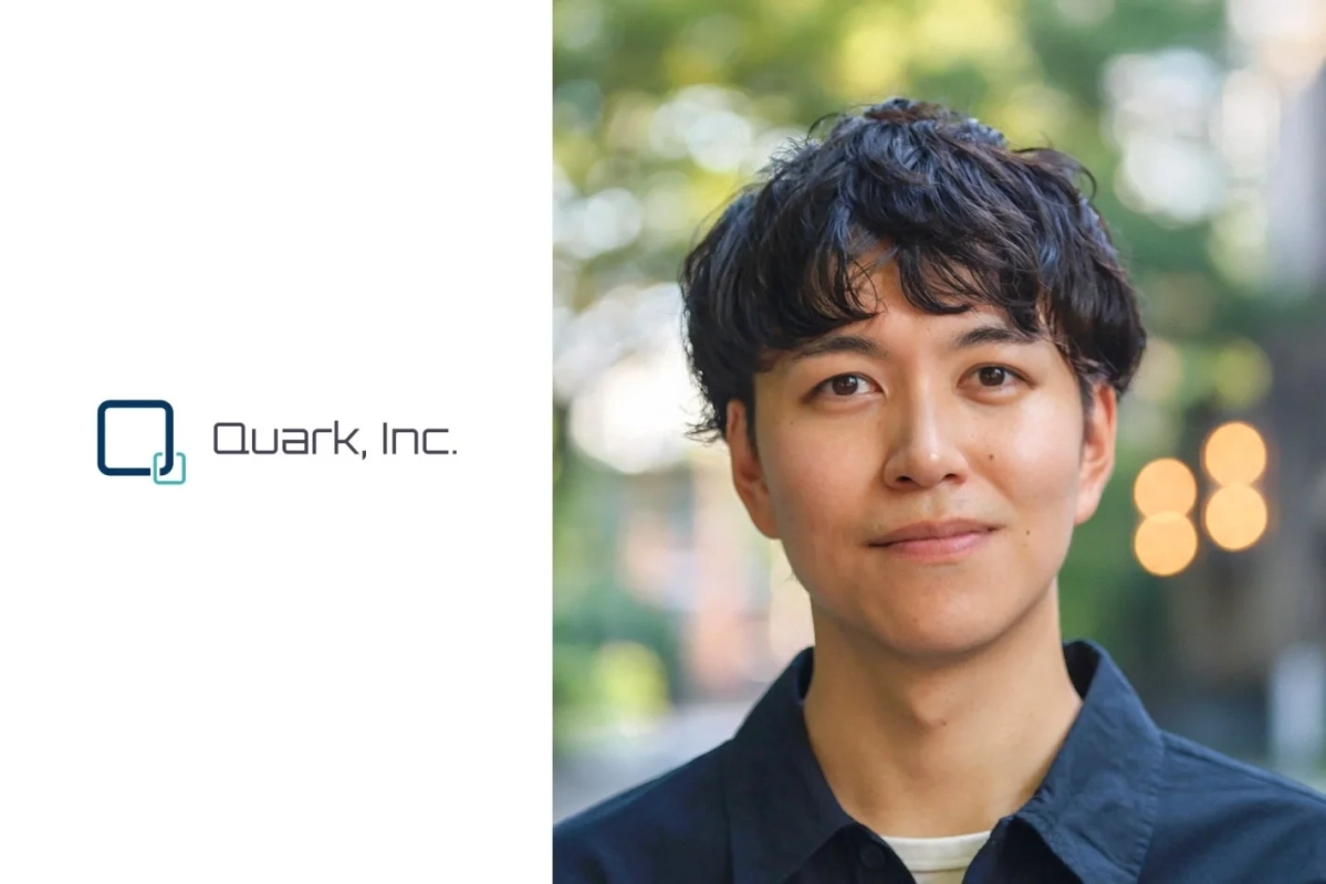 「Quark, Inc.」のロゴが配置された白い背景の横に、笑顔でカメラを見つめる若いアジア人男性の上半身