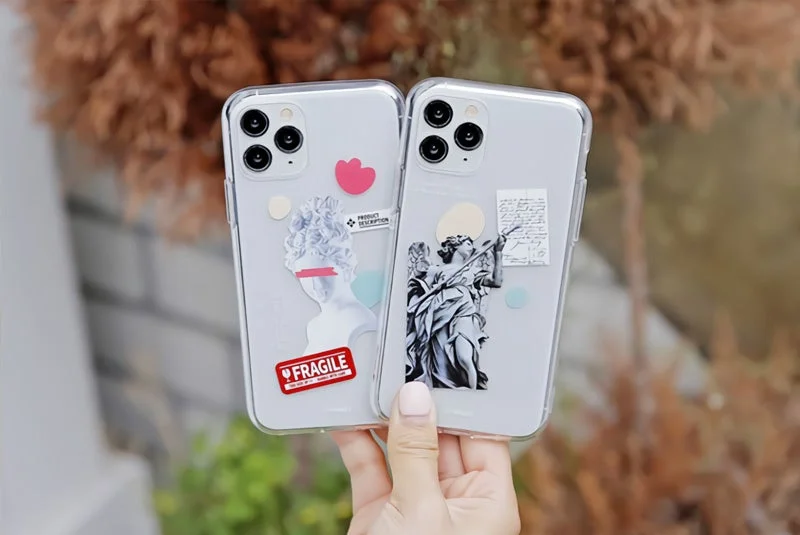 古典的な彫刻や天使のアートがデザインされた透明なiPhoneケースが2つ並べられています
