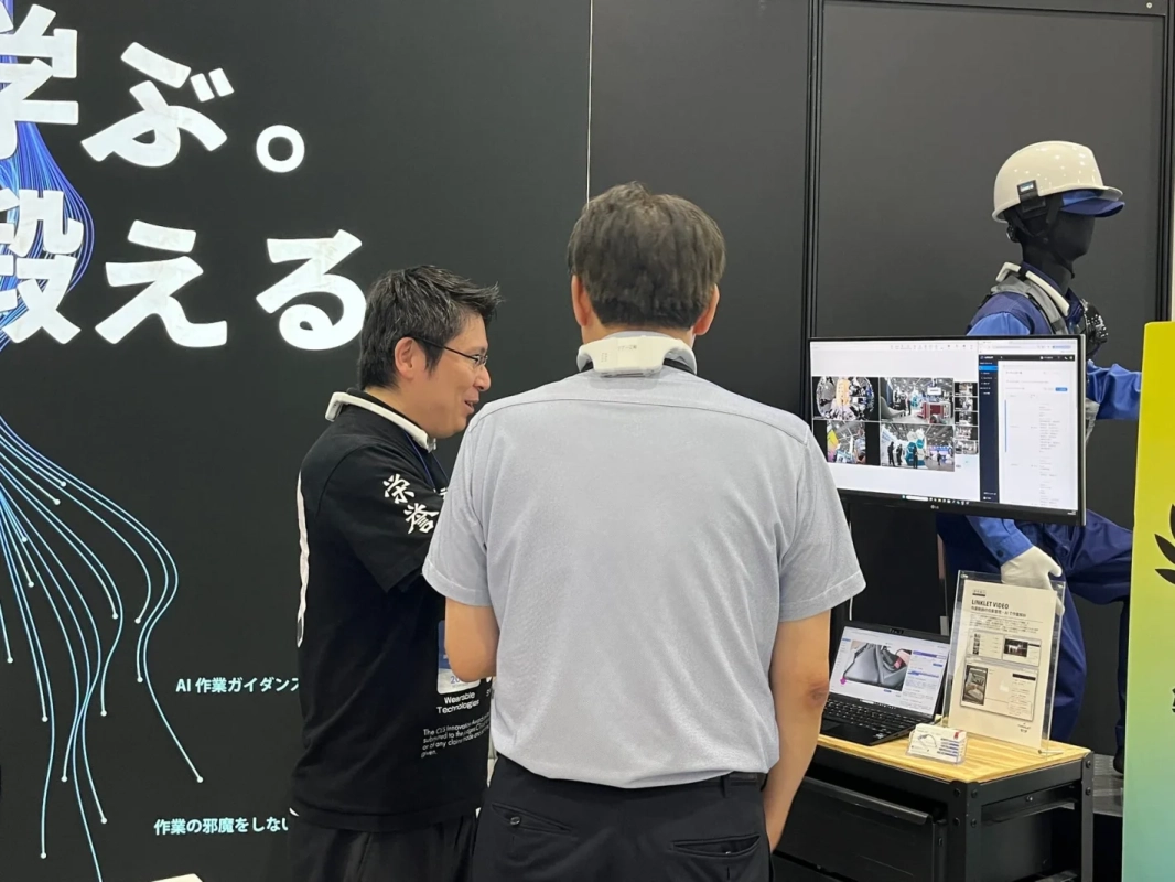 展示会ブースでAI作業ガイダンスについて説明を受ける様子