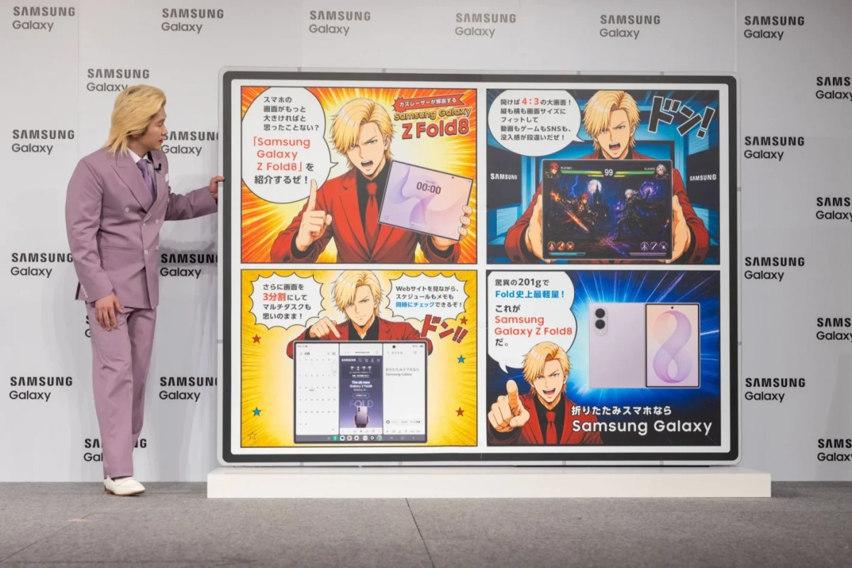 金髪の男性がパープルのスーツを着て、Samsung Galaxy Z Fold8の大型プロモーションディスプレイを指差している