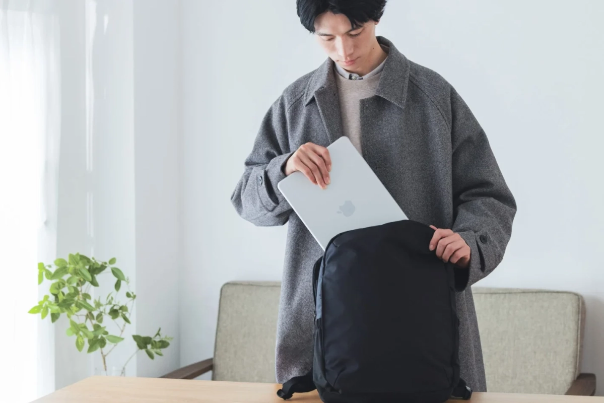 MacBookをリュックに入れる男性の様子
