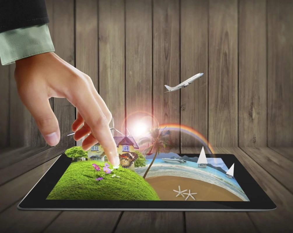 手がタブレットを操作し、画面から風景が飛び出しているような合成画像