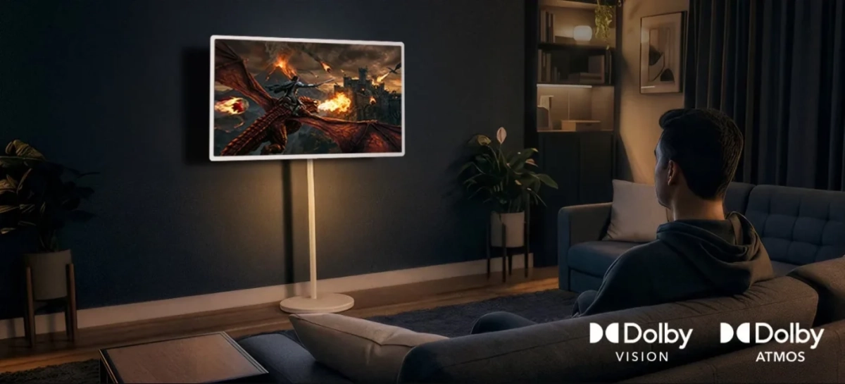 モダンなリビングルームで男性がテレビでファンタジーゲームを鑑賞している様子。Dolby VisionとDolby Atmosのロゴがあり、高品質な視聴体験を示唆しています。