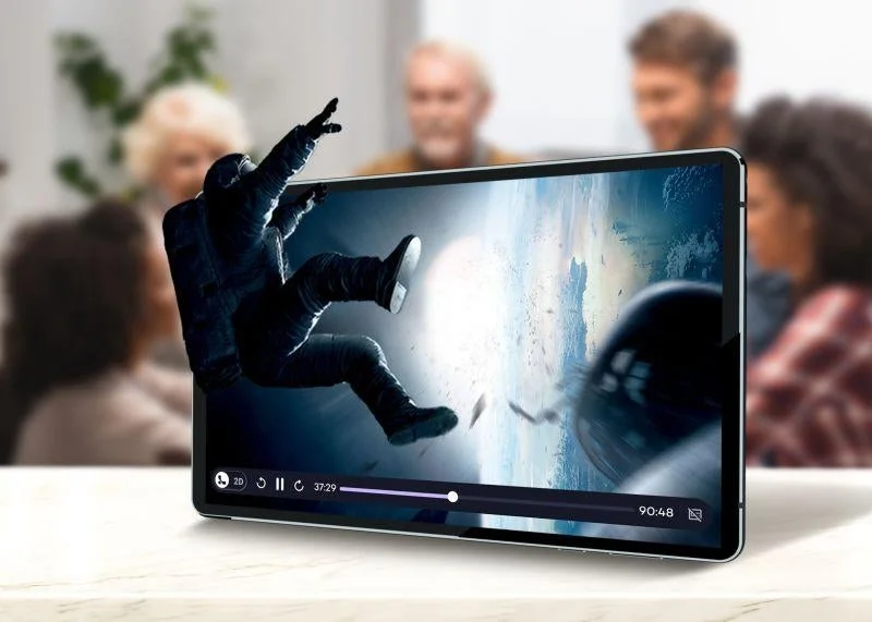 宇宙飛行士がタブレット画面から飛び出すような3D映像を映し出しており、その没入感あふれる視聴体験を複数の人々が楽しんでいる様子